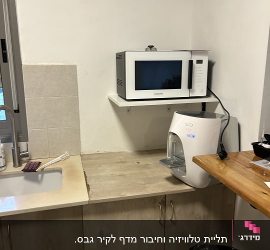 מטבח קטן עם מיקרוגל ומתקן מים על מדף